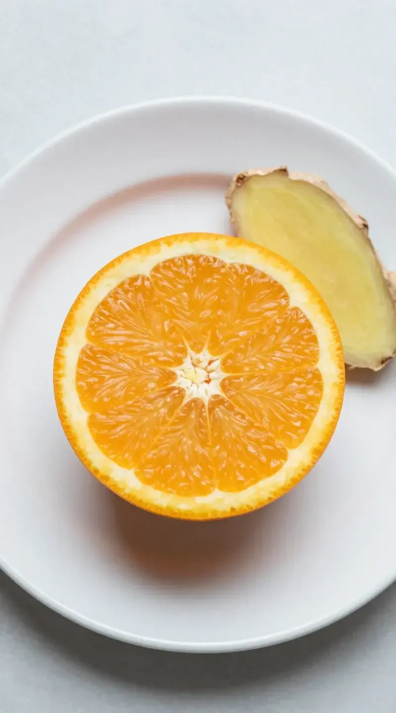Top view halved orange with ginger slice on white plate