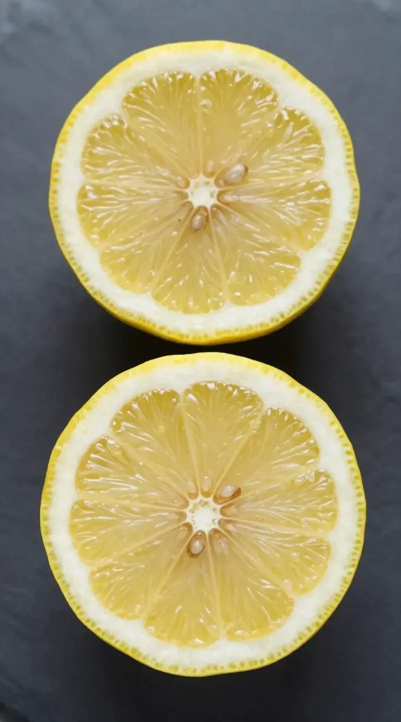 Overhead lemon half with visible zest oils on slate